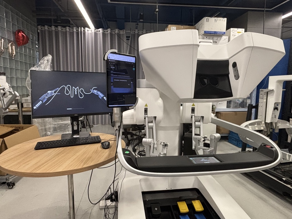 Surgical robot console beside a monitor displaying the instruments